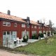 Foto av rekkehus på Malerhaugen. Vertikaldelte leiligheter. Rød trekledning, saltak.