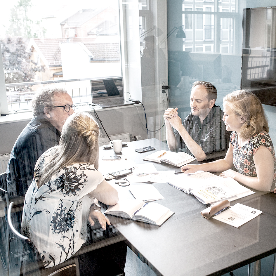En gruppe sitter og diskuterer inne på et møterom på Enerhaugen Arkitektkontor